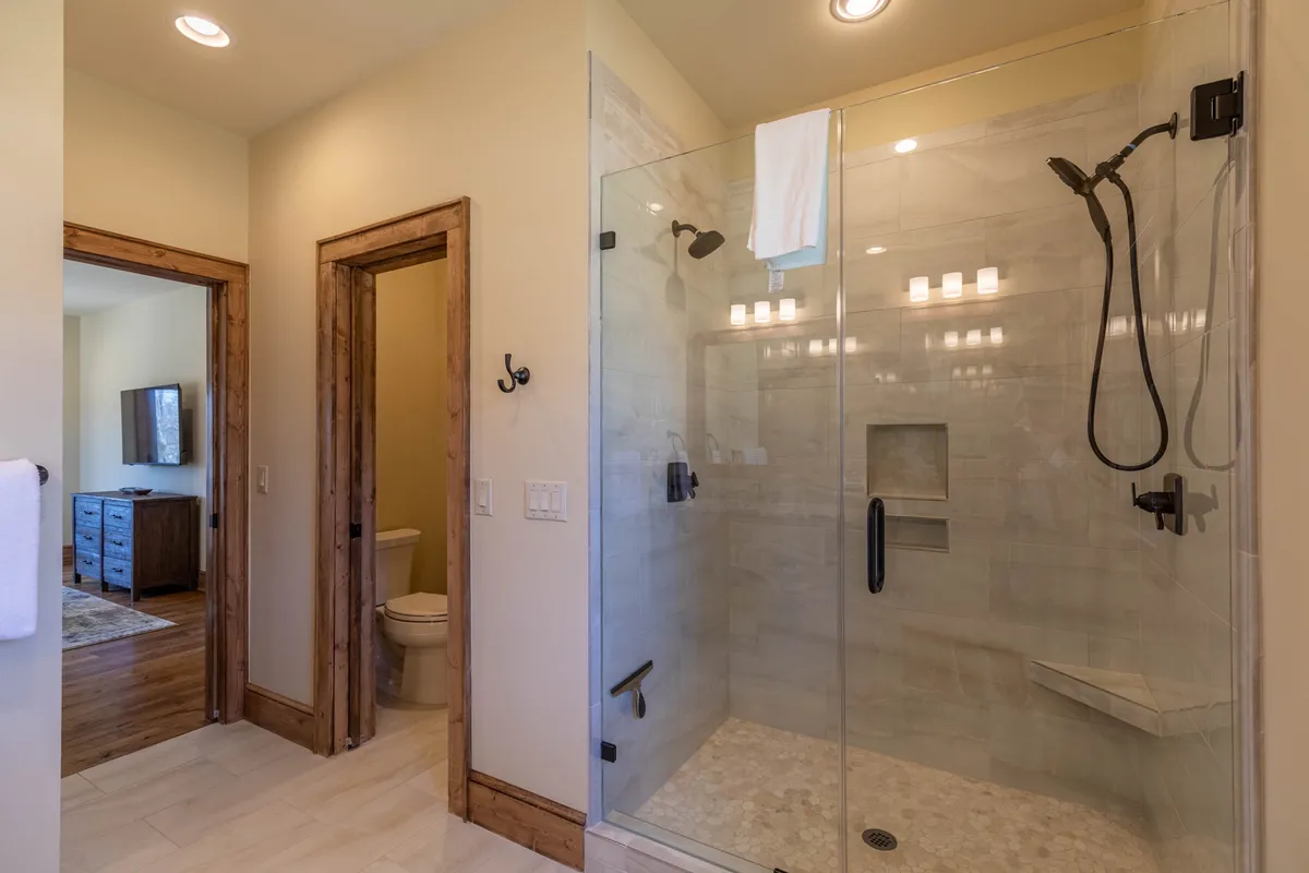 A modern, walk-in glass shower enclosure with a natural stone floor and wooden door frames, evoking a spa-like and rejuvenating experience—ideal for starting or ending the day in comfort.